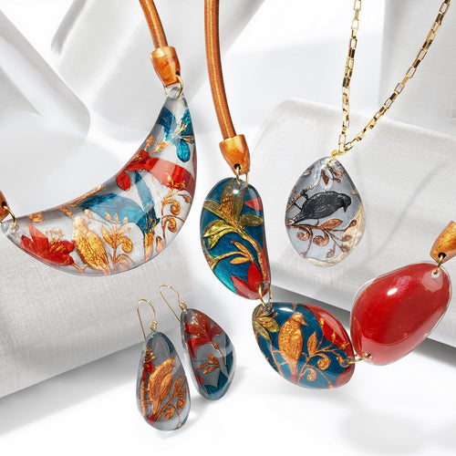 Helena collection — Gold-foil medallions printed with birds and blossoming branches, paired with a glossy accent bead on copper cord or gold chain.